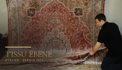 Artisan dépliant un grand tapis persan clair pour repérer les taches à traiter