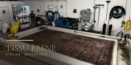 Grand tapis persan &eacute;tendu sur la table de lavage de l&rsquo;atelier Tissu &Eacute;b&egrave;ne, en r&eacute;gion parisienne