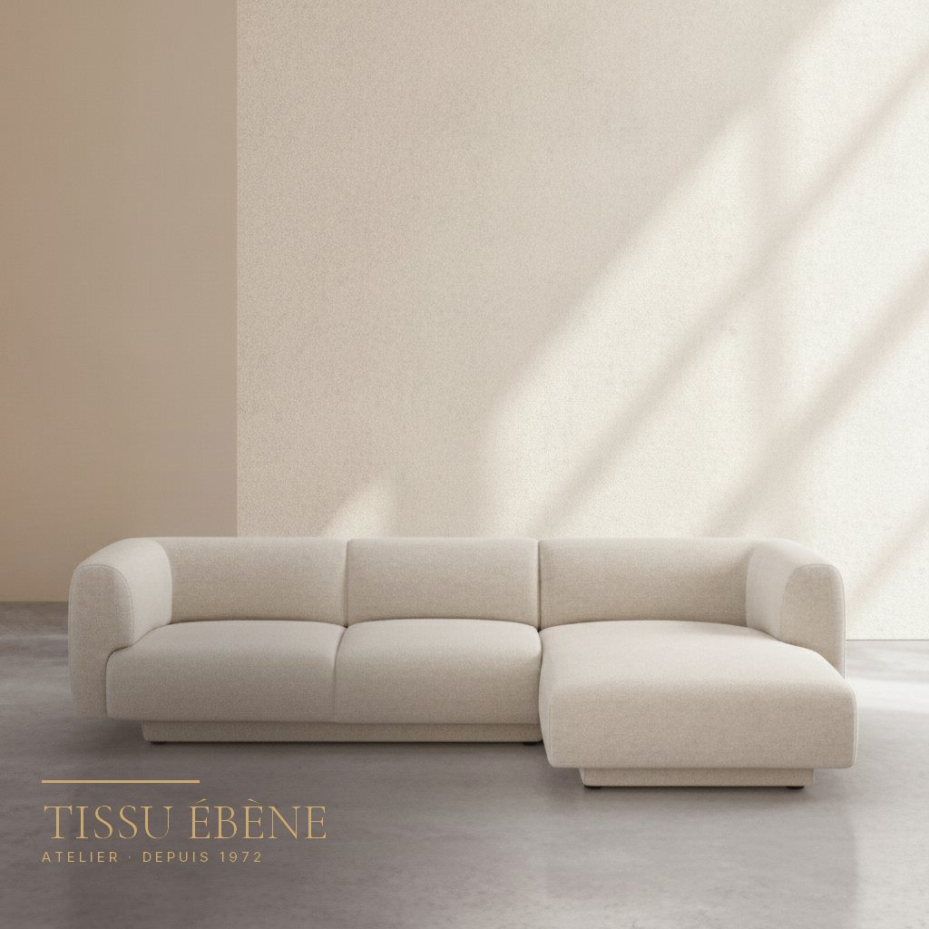 Canap&eacute; d&rsquo;angle en tissu boucl&eacute; cr&egrave;me aux formes arrondies devant un mur clair