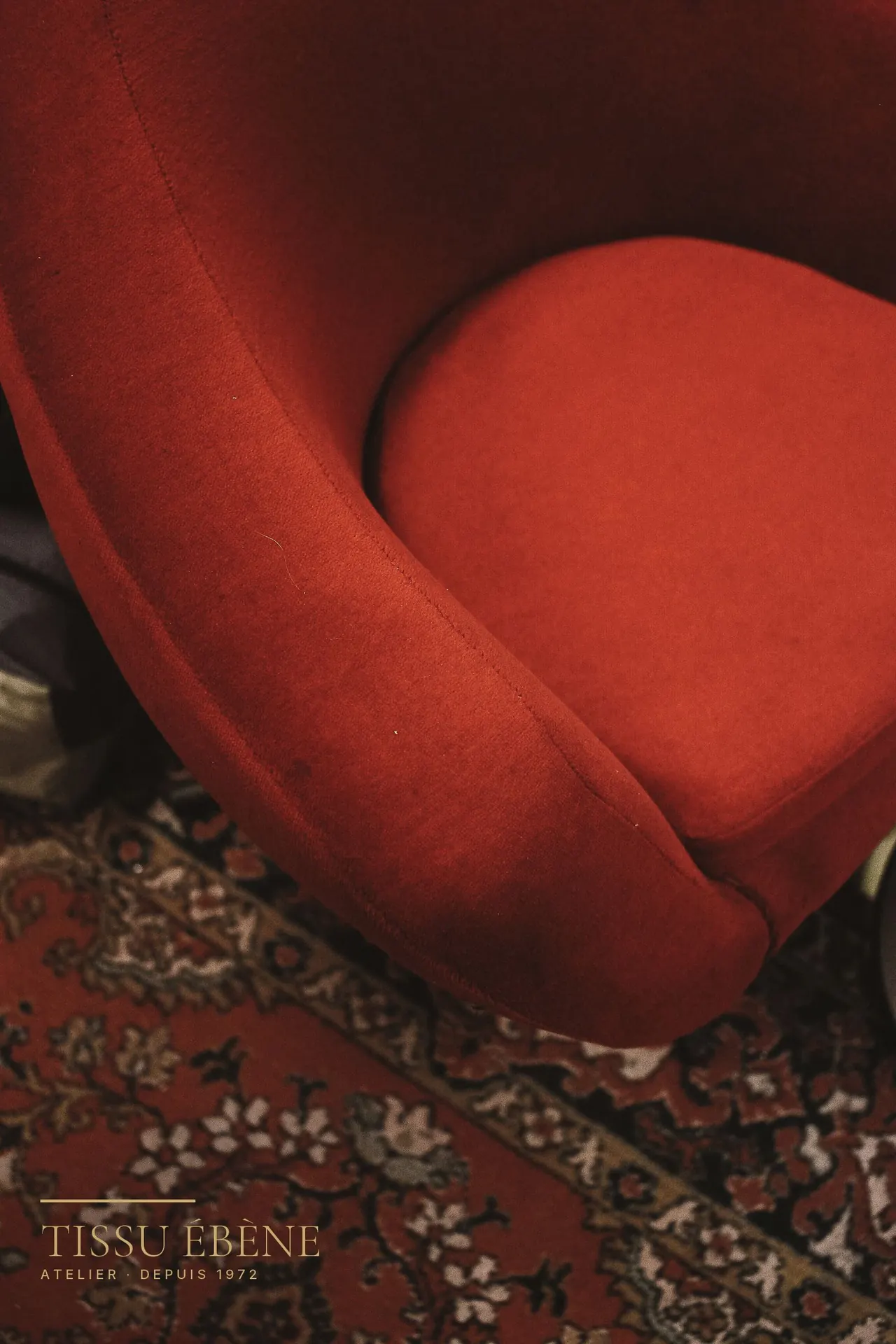 Assise et accotoir arrondis d&rsquo;un petit fauteuil crapaud en velours rouge