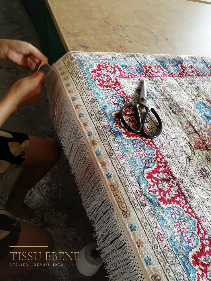 Franges d&rsquo;un tapis en soie refaites &agrave; la main, fil &agrave; fil, sur la table de l&rsquo;atelier