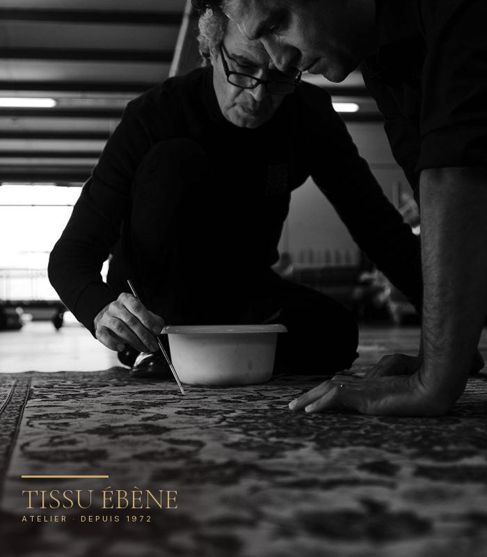 Artisans agenouill&eacute;s sur un tapis persan pour raviver une couleur au pinceau