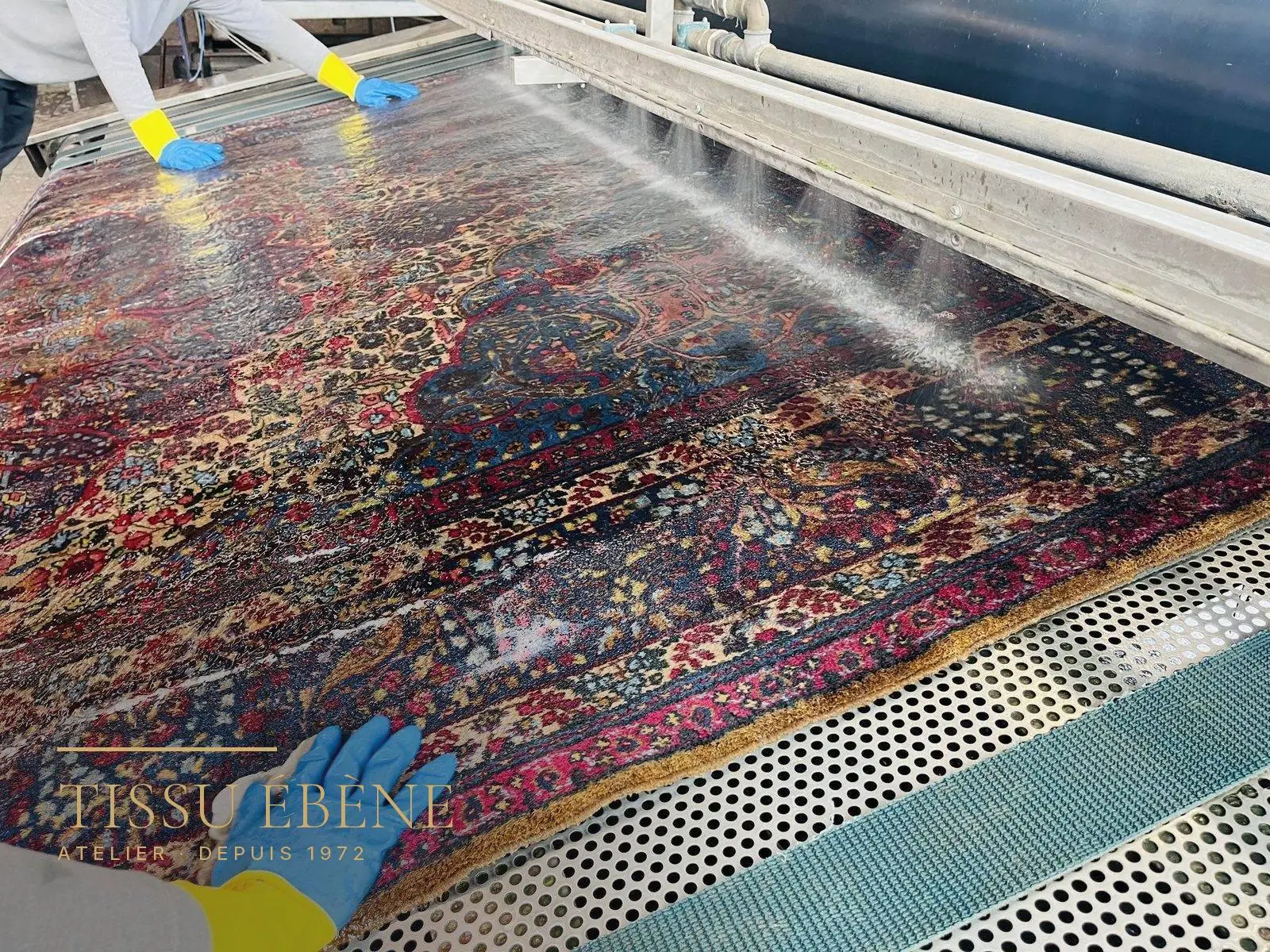 Tapis persan rinc&eacute; &agrave; l&rsquo;eau claire, &agrave; plat, sur la table de lavage de l&rsquo;atelier